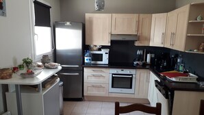 Cozinha compacta com geladeira, micro-ondas, forno e pia.