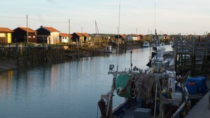 Uma marina com barcos atracados, casas de madeira ao longo da água e um rio calmo.