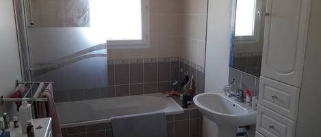 A bathroom with a bathtub, a sink, and a mirror.