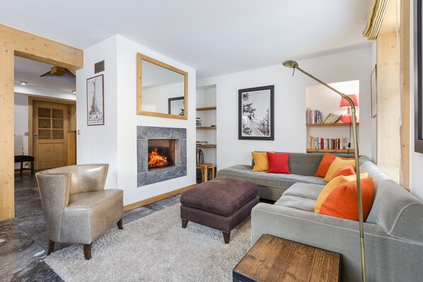 A modern living room with a fireplace, a sofa, a chair, and a coffee table.