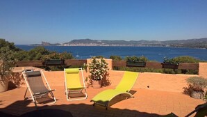 Una terraza con tres tumbonas frente a una vista costera.