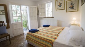 Un dormitorio con cama, una silla, un ventanal y un radiador.