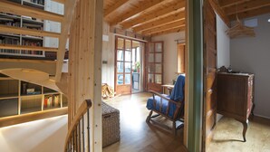 Ein Holzinterieur mit einer Treppe, Bücherregalen, einem blauen Sessel und einem Holzkabinett.