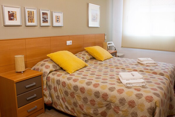 A hotel room with a bed, a nightstand, a lamp, and a chair.