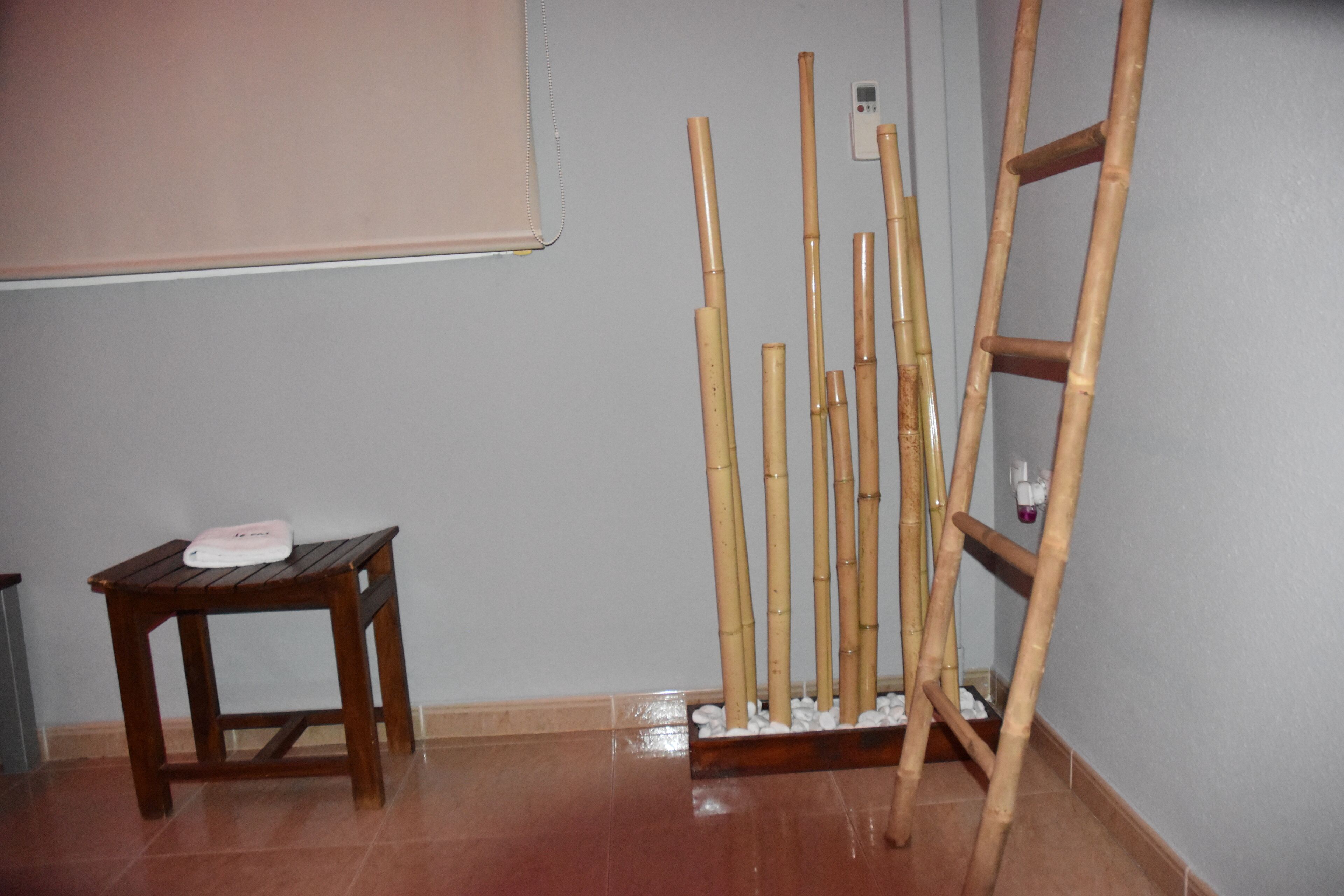 A room with a wooden table, a bamboo plant stand, and a ladder against the wall.