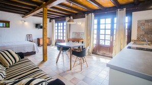 Une pi èce confortable avec un lit, une table à manger et des chaises, un coin cuisine et de grandes fenêtres.