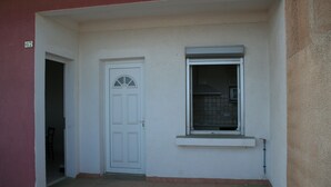 A building with a white door and a window with a metal grill. - Rents T3 - Leucate beach - Ground floor - Beachfront (Leucate)