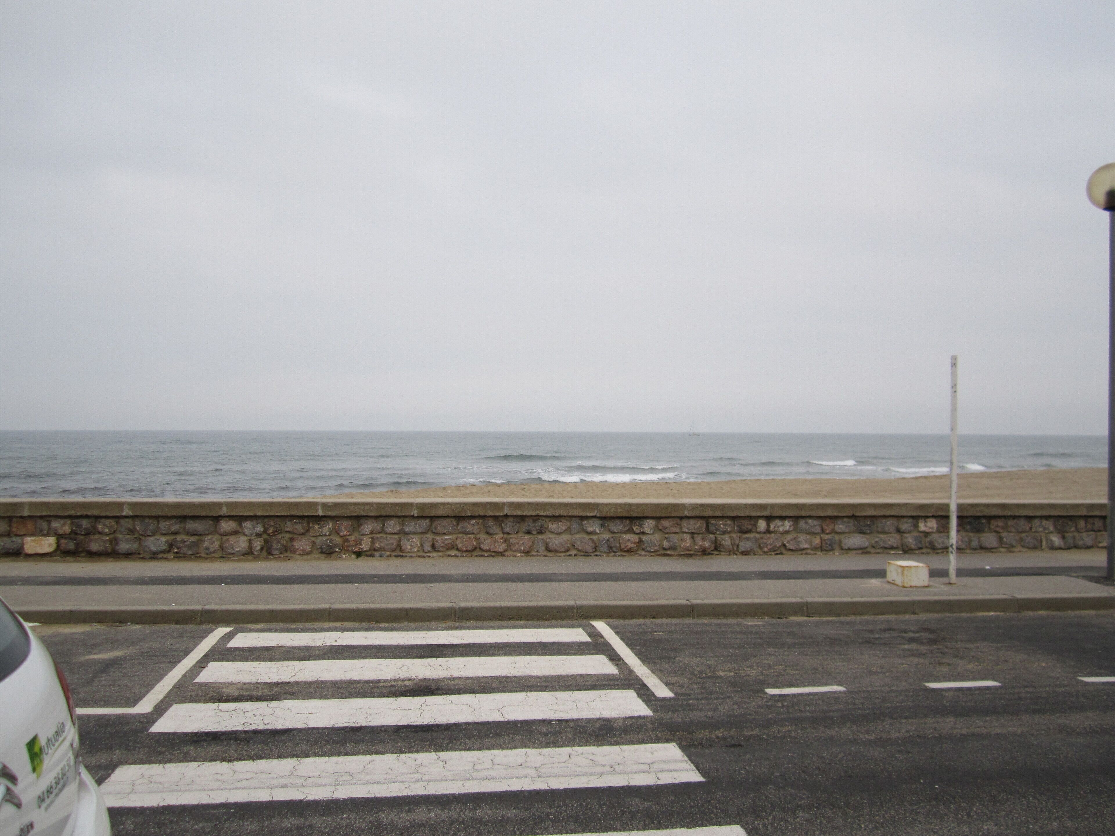 A coastal road with a pedestrian crossing leading to a beach.