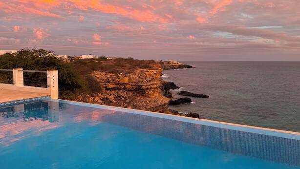 A pool with a view of the ocean and a rocky cliff. - Pretty villa on the island of Maio Cape Verde with panoramic views of  Atlantic (Vila do Maio)