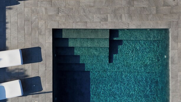 Una piscina en la azotea con agua cristalina, rodeada de baldosas de piedra.