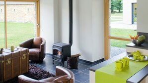 Ein modernes Wohnzimmer mit Kamin, Ledersessel und einem leuchtend grünen Tisch.