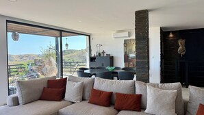 A modern living room with a sectional sofa, a dining area, and a view of a mountainous landscape.