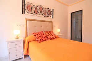 Een slaapkamer met een groot bed, twee nachtkastjes, een wandlamp en een aan de muur hangend kunstwerk.