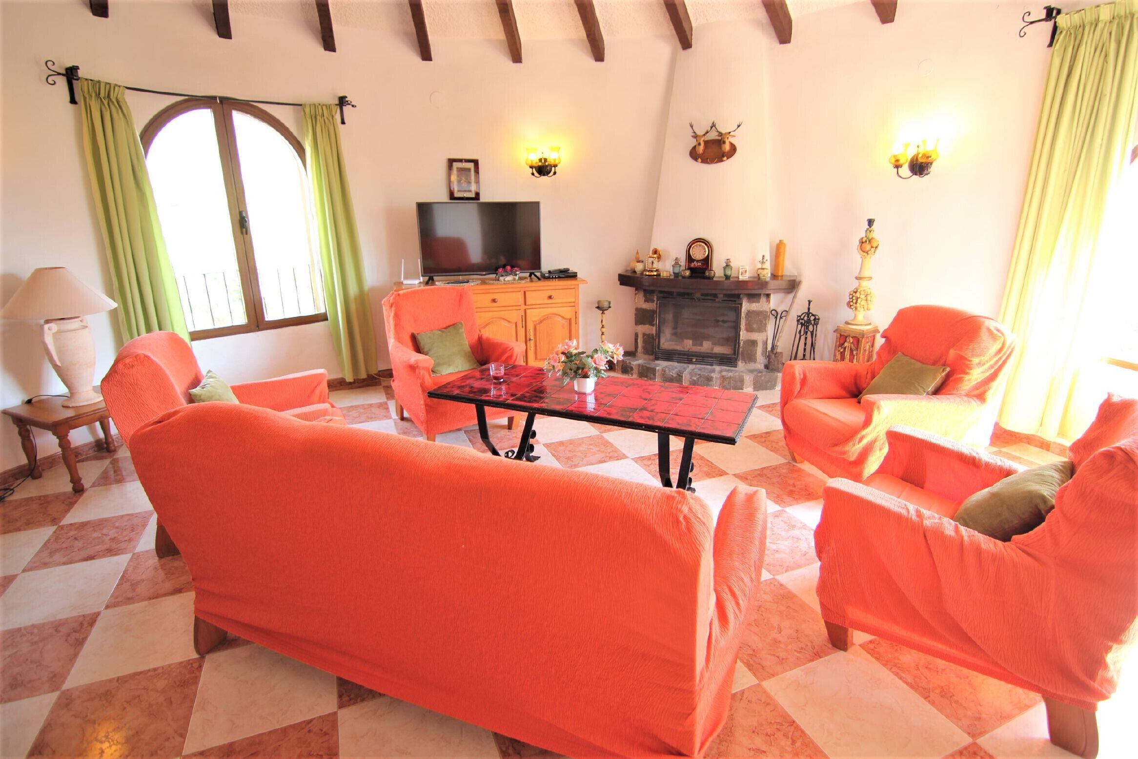 A living room with a checkered floor, orange sofas, a fireplace, and a television.