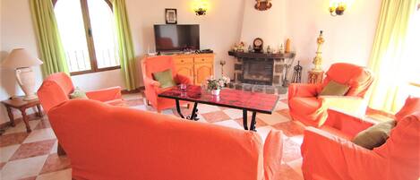A living room with a checkered floor, orange sofas, a fireplace, and a television.