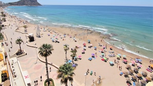 Une plage avec des palmiers, des parasols et des gens.