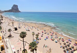 Een strand met palmbomen, parasols en mensen.
