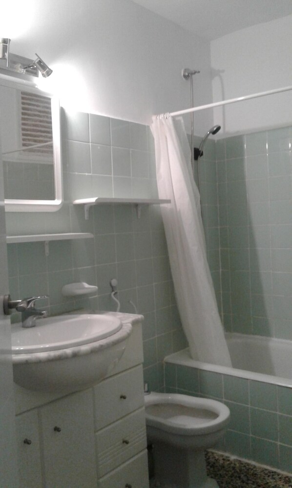 A bathroom with a sink, toilet, and shower area.