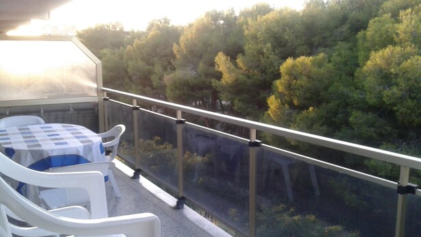 A balcony with a table and chairs, overlooking a forested area. - 100m2, 3 min from the beach, very good views. Ideal for families (Salou)