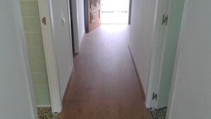 A narrow hallway with a wooden floor leading to a room with a door. - 100m2, 3 min from the beach, very good views. Ideal for families (Salou)