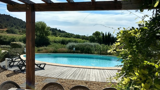 A wooden deck with a swimming pool, surrounded by greenery and hills.
