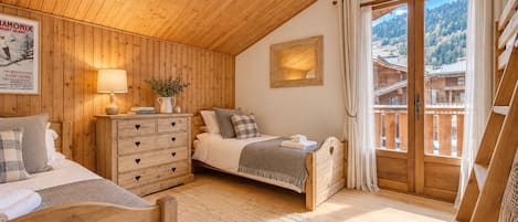 Un dormitorio acogedor con paredes de madera y un ventanal grande, un aparador con pomos con forma de corazón y una cama con cabecera con forma de corazón.