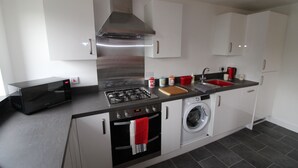 Una cucina moderna con piano cottura a gas, forno, microonde e lavatrice integrata.
