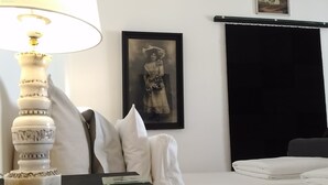 Une chambre d’hôtel bien rangée, avec un lit, une table de chevet dotée d’une lampe, un tableau encadré au mur et un rideau noir.