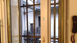 Une porte avec un portail en métal, un trou de serrure et une petite plaque fixée au mur.