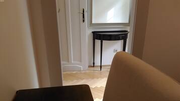 Una habitación con una puerta que da a un pasillo, un elegante escritorio consola negro y un espejo en la pared.