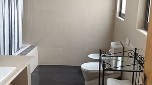 Et badeværelse med badekar, toilet og håndvask.