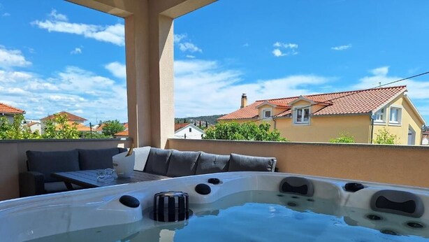 Un jacuzzi en un balcón con vistas a casas y un cielo despejado.