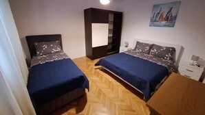 Un dormitorio con dos camas, un armario, una mesita de noche y un cuadro en la pared.