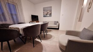 Una sala de estar con una mesa de comedor, sillas, un sofá y una televisión.