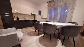 Una cocina moderna con armarios blancos, una mesa de comedor con cuatro sillas y un sofá.