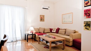A living room with a sofa, a coffee table, a lamp, and a bookshelf. - Acropolis area next Metro & Museum (Athina)