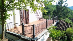 Un edificio blanco con balcón, una escalera y vistas a un área boscosa.