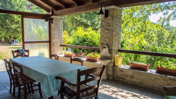 Un patio al aire libre con mesa y sillas, pilares de piedra y plantas en macetas.
