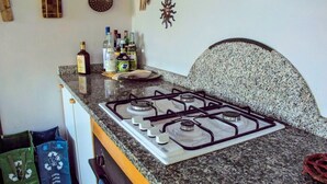 Una cocina con estufa a gas, encimera de granito y varias botellas sobre la encimera.