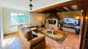 Una sala de estar con un sofá, una chimenea, un televisor y una pared de piedra.