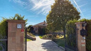 Una entrada protegida por un portón, con un camino despejado que lleva a una casa.