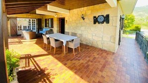 Un patio al aire libre con una pared de piedra, una mesa con sillas y vistas al campo.