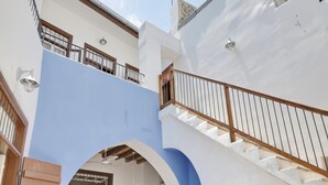 Ein mehrgeschossiges Gebäude mit blau-weißer Farbgebung, das Balkone, Geländer und eine Treppe zeigt.