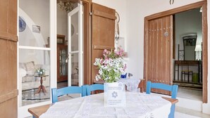 Ein Essbereich mit einem Tisch für zwei Personen, einer Blumenvase und einem Schild, das auf eine traditionelle Touristenunterkunft hinweist.