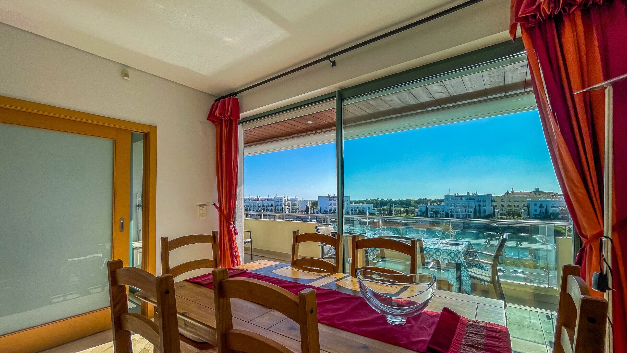 Un balcon avec une table dressée pour le dîner, une chaise et une vue sur le paysage urbain.