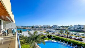 A balcony with a pool, a view of the marina, and buildings in the background.