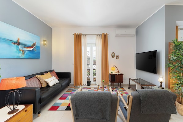 A living room with a sofa, a TV, a lamp, and a painting.