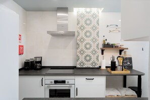 A modern kitchen with a built-in oven, a coffee maker, and a stainless steel range hood.