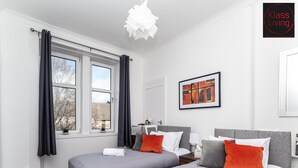 A modern hotel room with two beds, a large window, a painting, and a white pendant light. - One Bedroom Apartment by Klass Living Serviced Accommodation Rutherglen - Crossroads Apartment With WiFi and Parking (Glasgow)