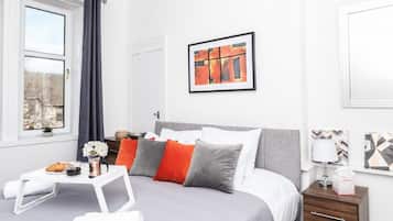 Quarto moderno com cama, mesa de cabeceira e janela com cortinas.